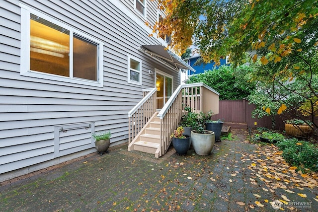 view of property exterior with a patio, fence, and a wooden deck