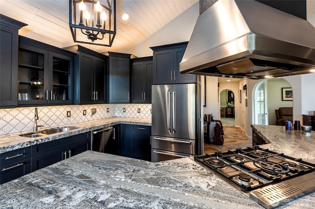 kitchen with high end refrigerator, arched walkways, extractor fan, stovetop, and a sink