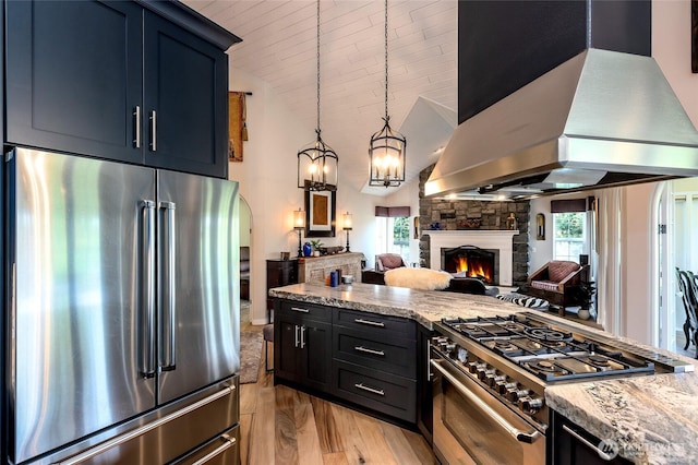 kitchen featuring premium appliances, exhaust hood, light wood-style floors, open floor plan, and a wealth of natural light