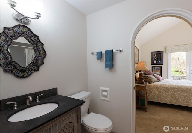 bathroom featuring lofted ceiling, vanity, toilet, and ensuite bathroom