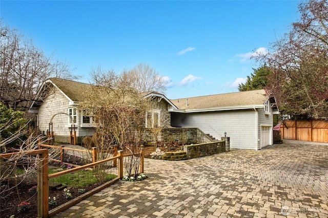 back of house with a garage, fence, and decorative driveway