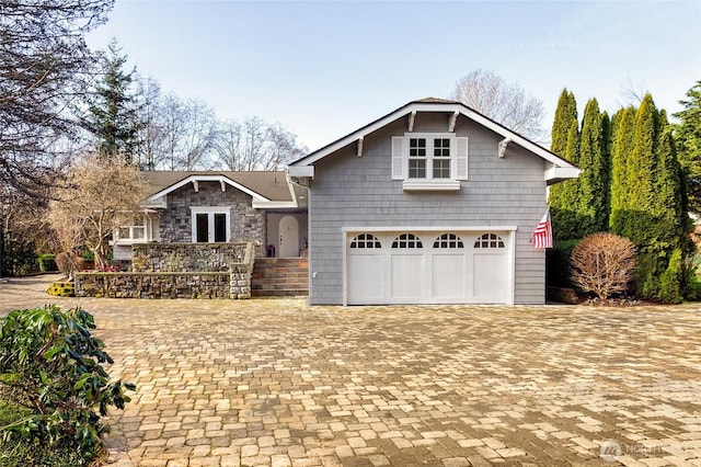 view of front of property featuring a garage, stone siding, and decorative driveway