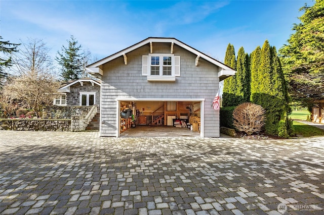 view of side of property with an attached garage and decorative driveway