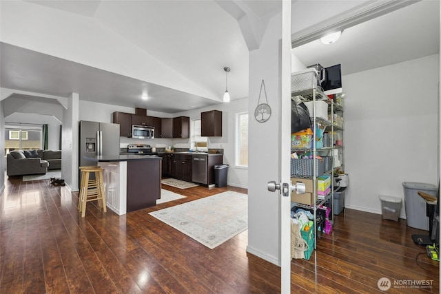 kitchen featuring dark wood-style flooring, a kitchen island, vaulted ceiling, dark brown cabinets, and appliances with stainless steel finishes