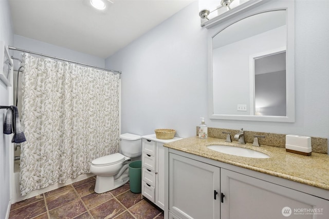 full bathroom featuring toilet, stone finish flooring, vanity, and shower / tub combo with curtain