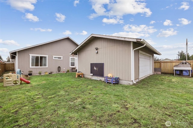 back of house with an outbuilding, a detached garage, a lawn, fence, and driveway