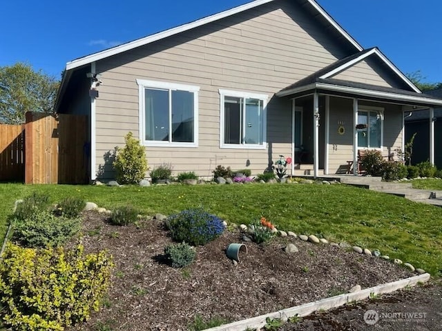 bungalow-style home with a front lawn, covered porch, and fence