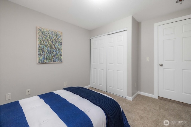 carpeted bedroom featuring a closet and baseboards