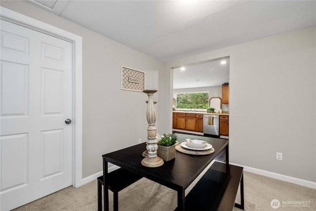 dining space featuring light carpet and baseboards