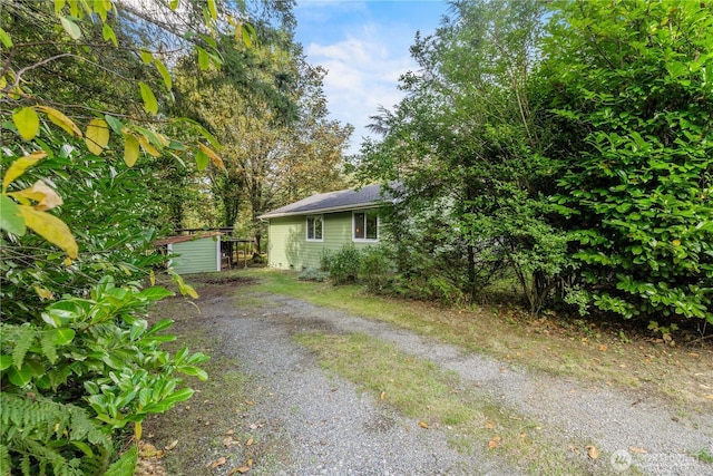 view of home's exterior with an outbuilding, gravel driveway, and a storage unit