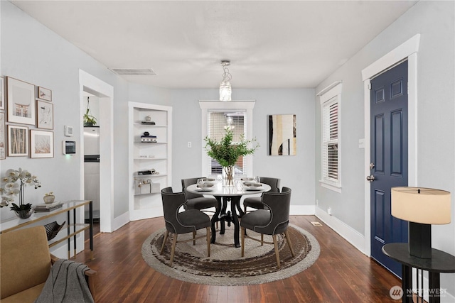 dining area with baseboards, visible vents, built in features, and dark wood finished floors