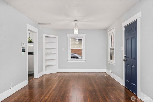 unfurnished dining area featuring baseboards, hardwood / wood-style floors, visible vents, and built in features