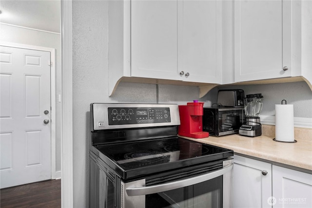 kitchen featuring dark wood-type flooring, light countertops, white cabinets, and stainless steel electric range