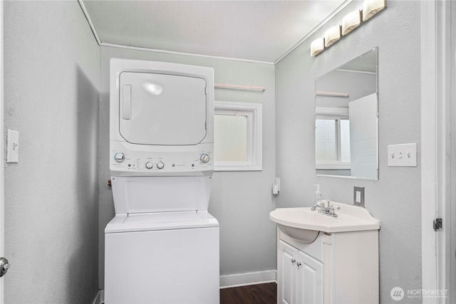 interior space with stacked washer / dryer, wood finished floors, vanity, and baseboards