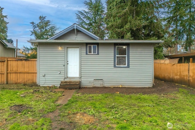 back of house featuring entry steps, a fenced backyard, and a yard