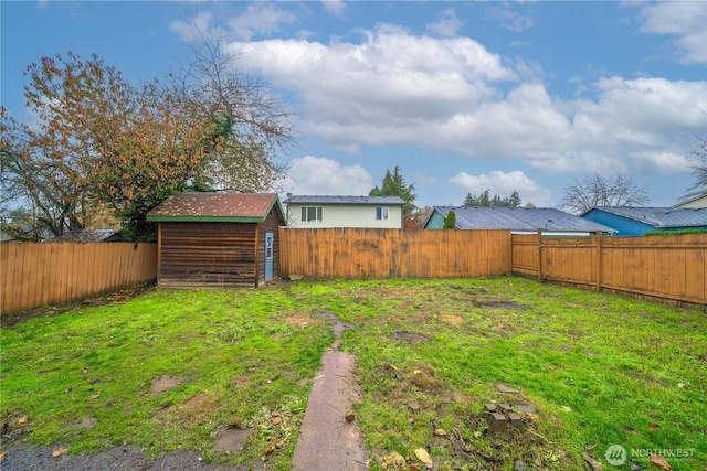 view of yard featuring an outbuilding, a storage shed, and a fenced backyard