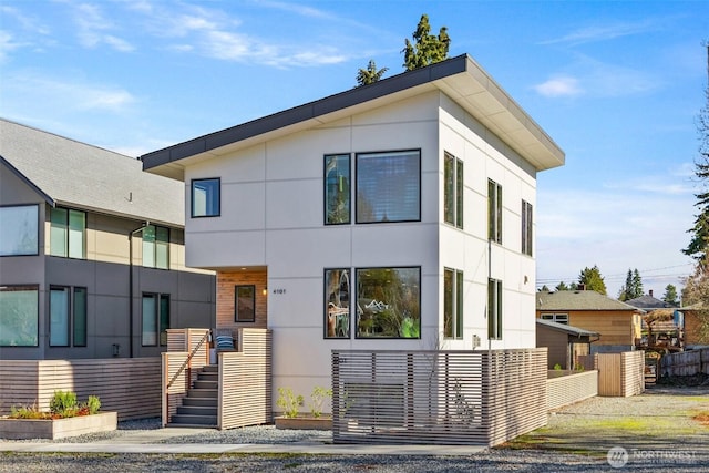 contemporary home with fence and stucco siding