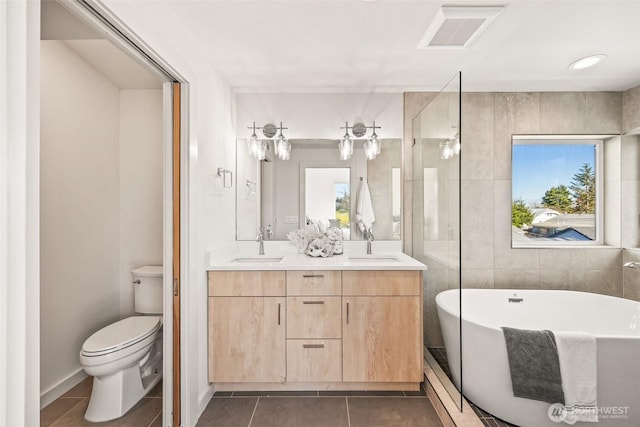 bathroom with tile patterned flooring, toilet, a sink, visible vents, and double vanity