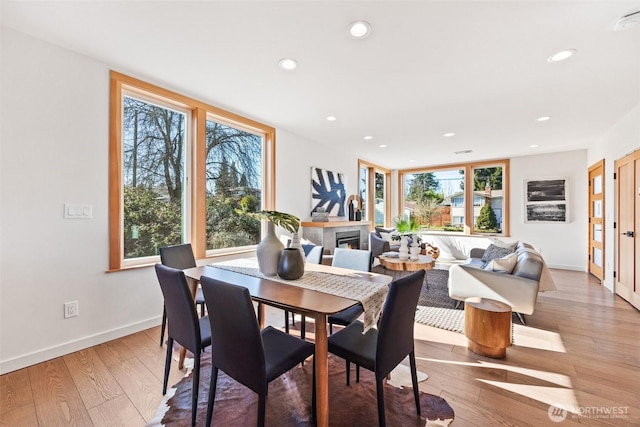 dining area with hardwood / wood-style flooring, baseboards, a glass covered fireplace, and recessed lighting