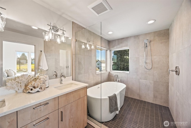 full bath with tile walls, visible vents, a freestanding bath, a tile shower, and vanity