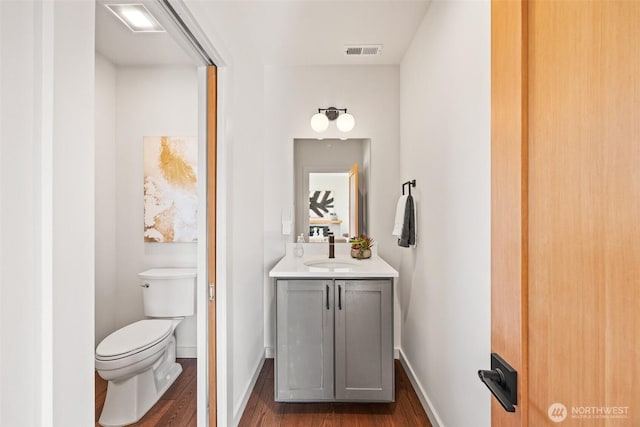 bathroom with visible vents, toilet, vanity, wood finished floors, and baseboards