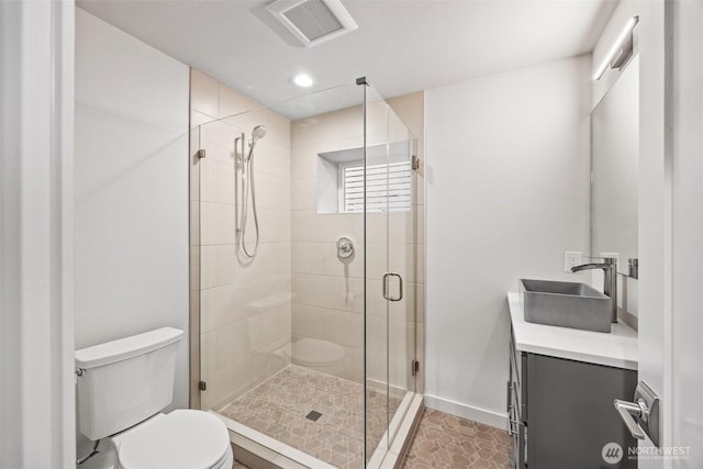 bathroom featuring a stall shower, baseboards, visible vents, toilet, and vanity