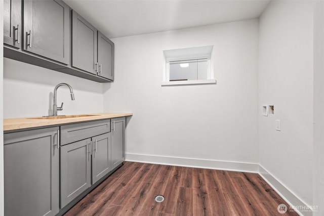 washroom with hookup for a washing machine, dark wood-style flooring, a sink, and baseboards