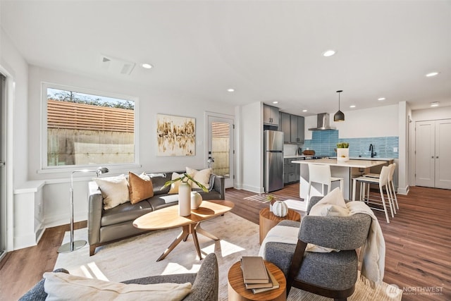 living room featuring recessed lighting, visible vents, baseboards, and wood finished floors