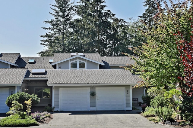 view of front of property with aphalt driveway, an attached garage, and roof with shingles