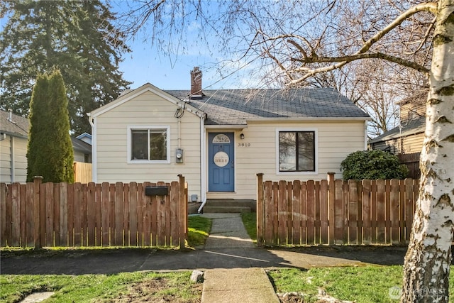 bungalow-style house with entry steps, a shingled roof, a chimney, and fence