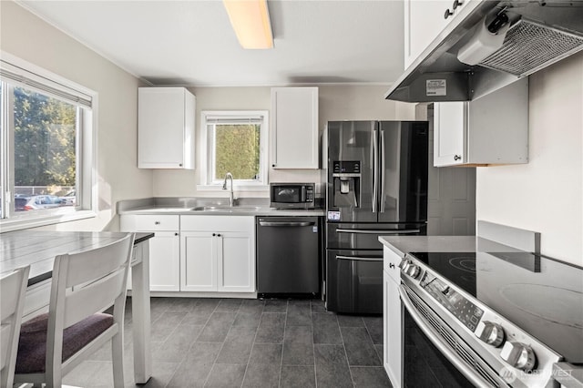 kitchen with stainless steel appliances, stainless steel counters, white cabinets, a sink, and under cabinet range hood