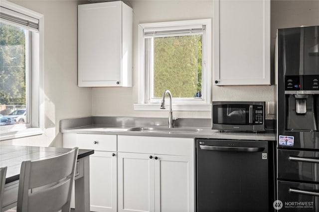 kitchen with a sink, white cabinets, dishwasher, black refrigerator with ice dispenser, and stainless steel microwave