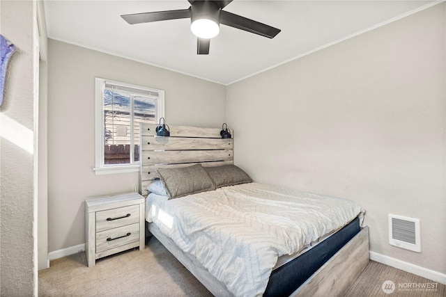 bedroom featuring crown molding, visible vents, a ceiling fan, light carpet, and baseboards