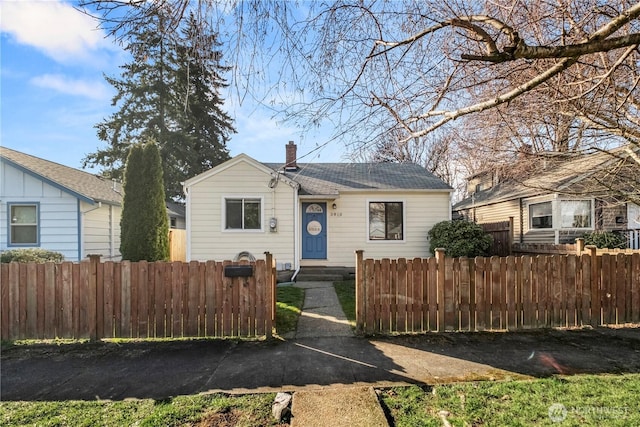 bungalow-style home with a fenced front yard and a chimney