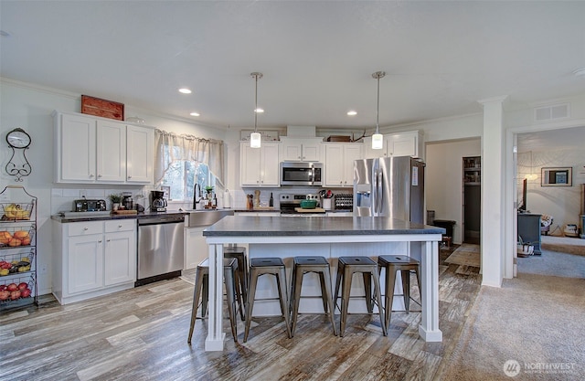 kitchen with visible vents, dark countertops, a kitchen breakfast bar, stainless steel appliances, and white cabinetry