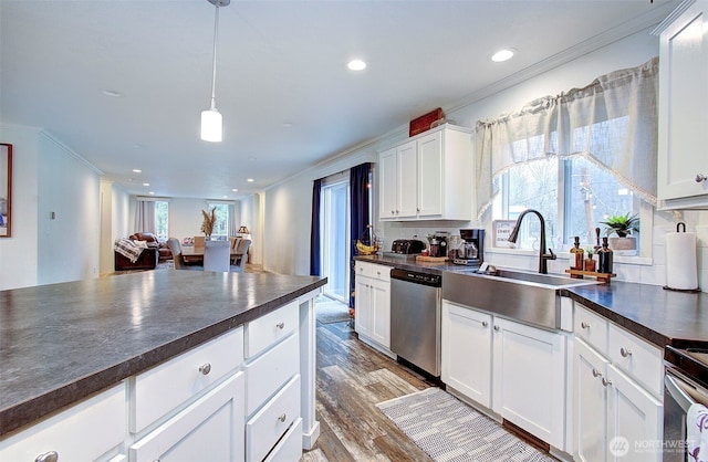 kitchen featuring appliances with stainless steel finishes, dark countertops, crown molding, and a sink