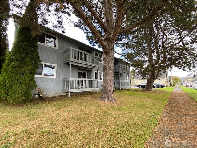 rear view of property featuring a lawn and a balcony