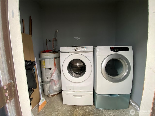 laundry room with strapped water heater, washing machine and clothes dryer, and laundry area