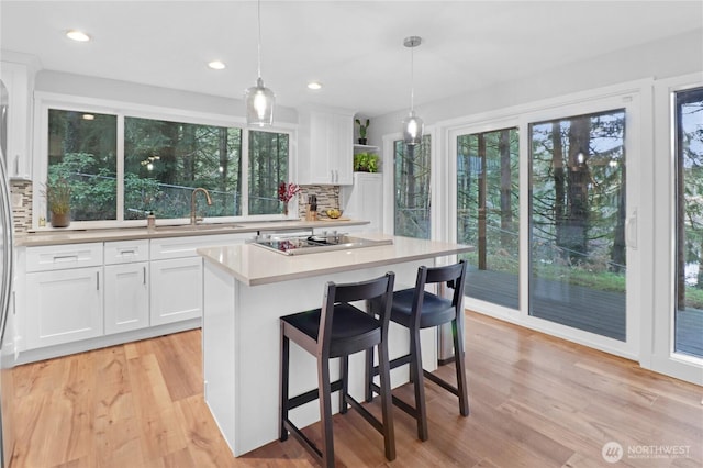 kitchen featuring white cabinets, electric cooktop, a sink, and light wood finished floors