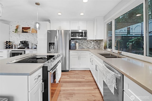 kitchen with wine cooler, stainless steel appliances, light wood-style flooring, white cabinets, and a sink