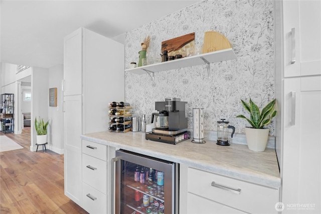 bar featuring a dry bar, light wood-style floors, beverage cooler, and wallpapered walls