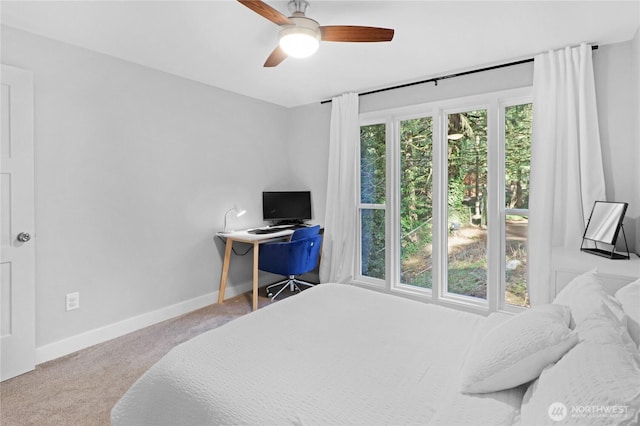 carpeted bedroom featuring multiple windows, a ceiling fan, and baseboards