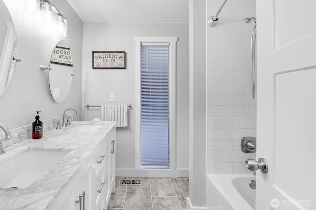 bathroom with shower / bath combination, visible vents, a sink, and baseboards