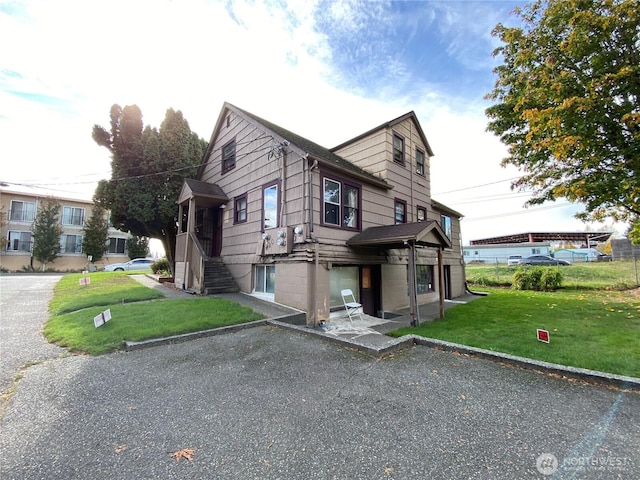 view of side of home featuring driveway and a lawn