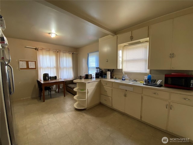 kitchen with light countertops, beam ceiling, a sink, and a wealth of natural light