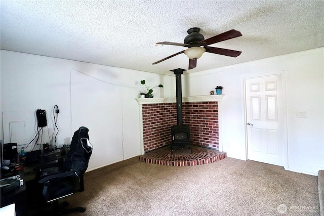 home office with a wood stove, a textured ceiling, a ceiling fan, and carpet flooring