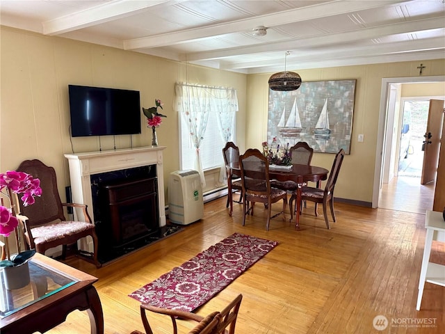 interior space with a fireplace, beamed ceiling, light wood-style floors, and a baseboard radiator