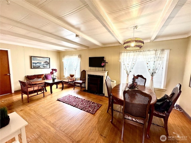 dining area featuring beamed ceiling, wood finished floors, and a fireplace