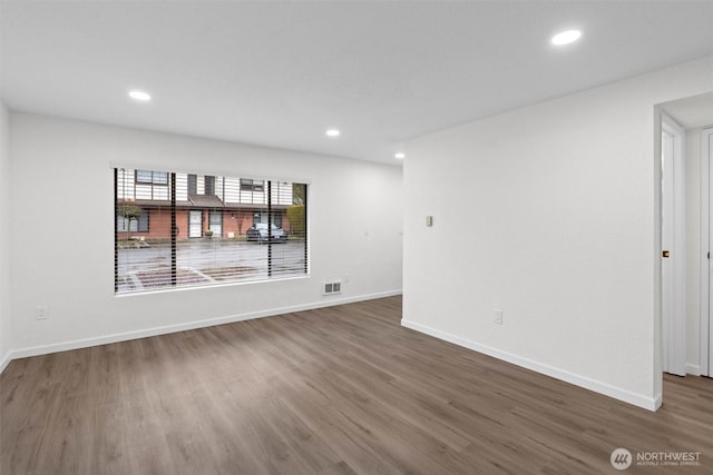 empty room with baseboards, wood finished floors, and recessed lighting