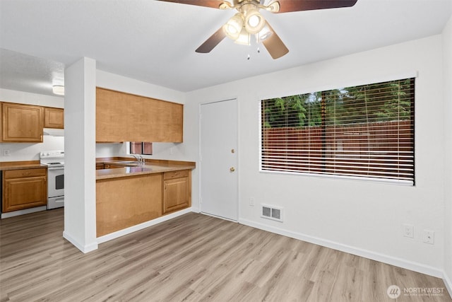 kitchen with visible vents, light wood-style floors, electric stove, light countertops, and brown cabinetry